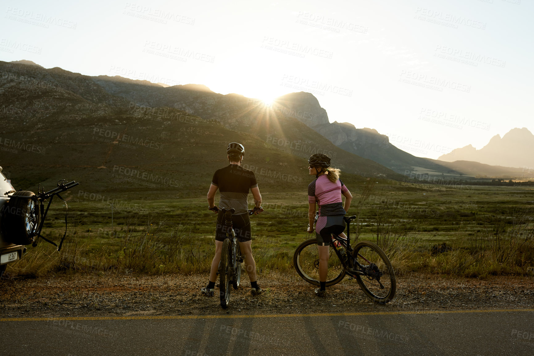 Buy stock photo Morning, mountain and back of couple on bicycle for sports hobby, outdoor exercise and workout. Sunrise, flare and man with woman on bike in countryside for cycling, wellness and fitness in nature