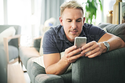 Buy stock photo Man, phone and laying on sofa in home, relax and scroll with chat, notification or texting in lounge. Mature person, smartphone and search mobile on app for video, contact and social media at house
