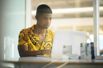 Buy stock photo Shot of a young businessman working on a laptop in an office