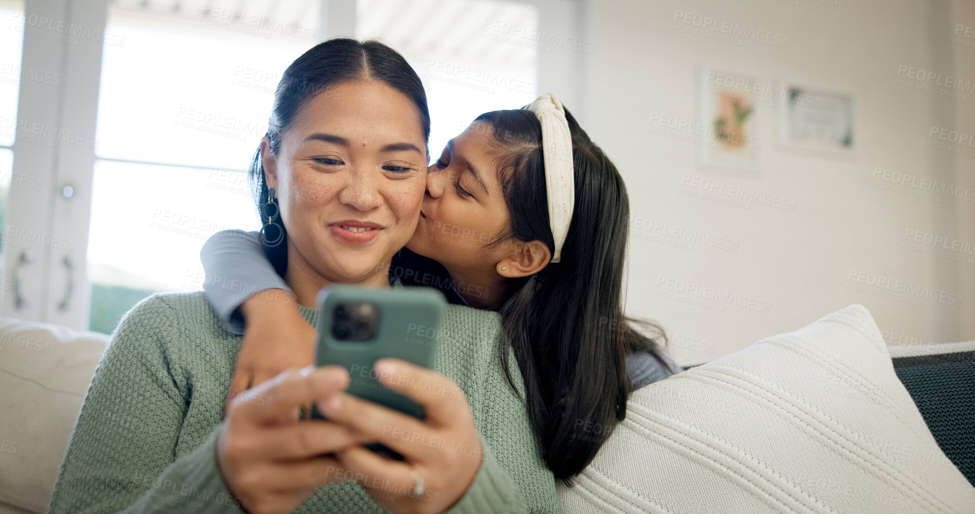 Buy stock photo Phone, mother and child on sofa with kiss, hug and love connection for social media browsing. Asian family, happy mom and kid in home with affection, healthy relationship or online reels with bonding