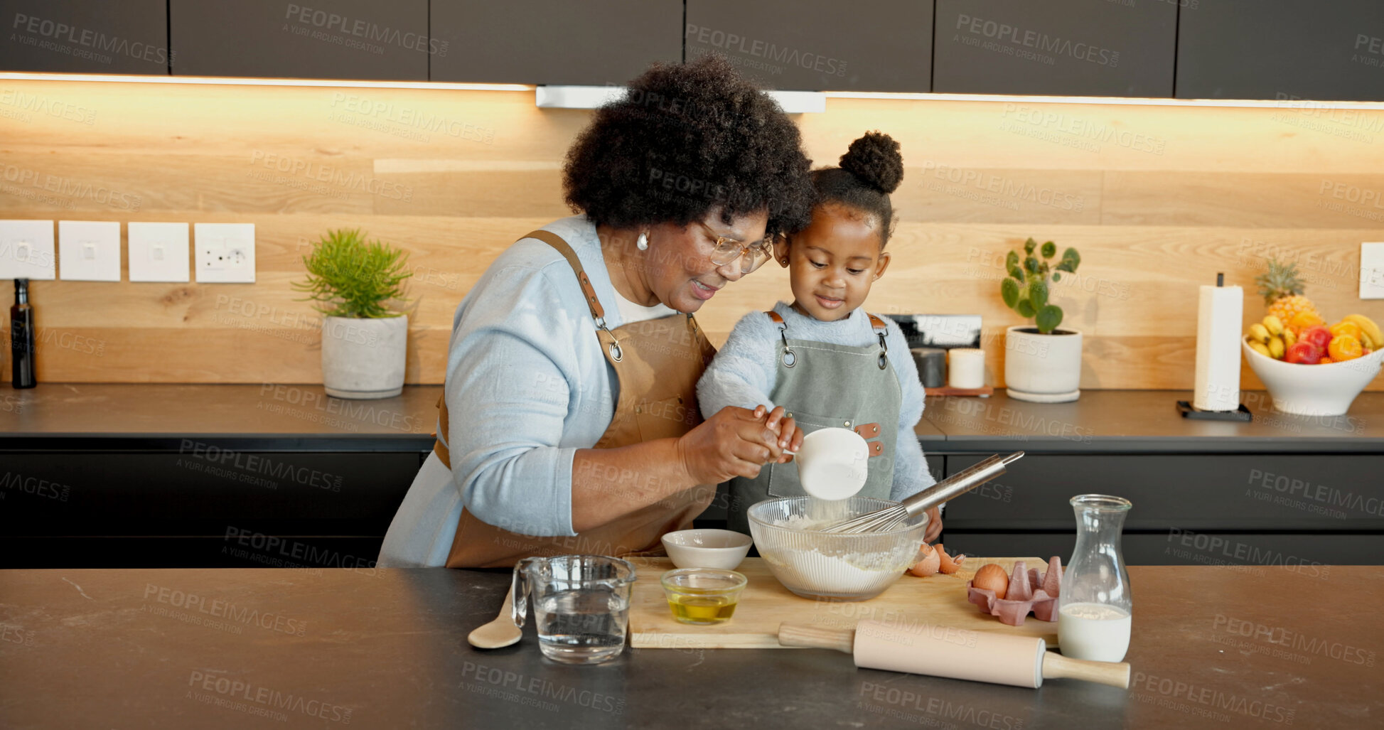 Buy stock photo Grandmother, child and baking in kitchen with flour, teaching and support with black family. Girl, grandma or pour ingredients in bowl for help with guidance, development or learning cooking at house