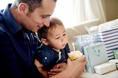 Buy stock photo Dad, child and cupcake with candle for blowing, childhood and bonding on sofa in home. Father, son and wish for celebration, love and fun in living room of house for event together with presents