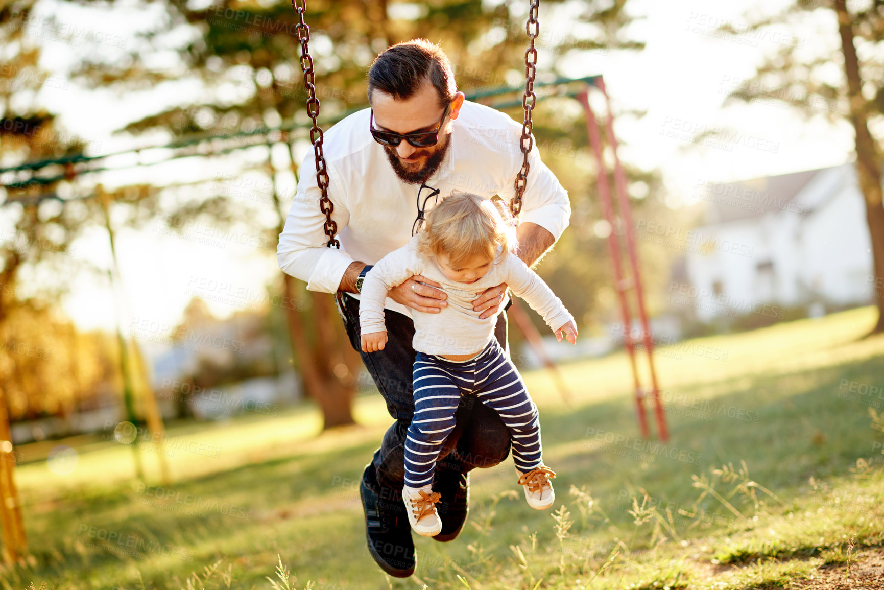 Buy stock photo Playground, swing and dad with girl in park for bonding, playing games and having fun outdoor. Family, sunlight and father with toddler to relax together on holiday, adventure and activity on weekend
