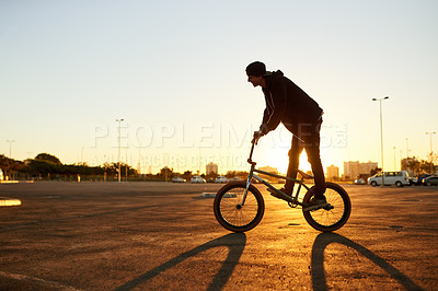 Buy stock photo Athlete, man and cycling bicycle in city for travel, endurance training and cardio exercise at space. Person, sunset and bike for fitness, sports workout and sustainable transport with stunt practice