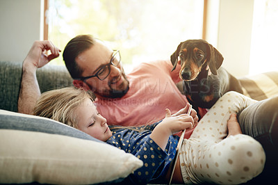 Buy stock photo Tablet, dog and relax with father with daughter on sofa for bonding, support and animal care. Happy, loyalty and pet owner with man and child with puppy in family house for trust, online and love