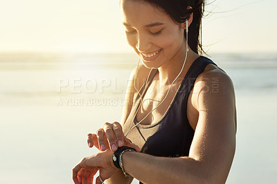 Buy stock photo Smart watch, fitness and woman at beach with music, check exercise progress or heart rate at sunset. Smile, wristwatch and sports athlete outdoor for steps, workout results and pulse for body health