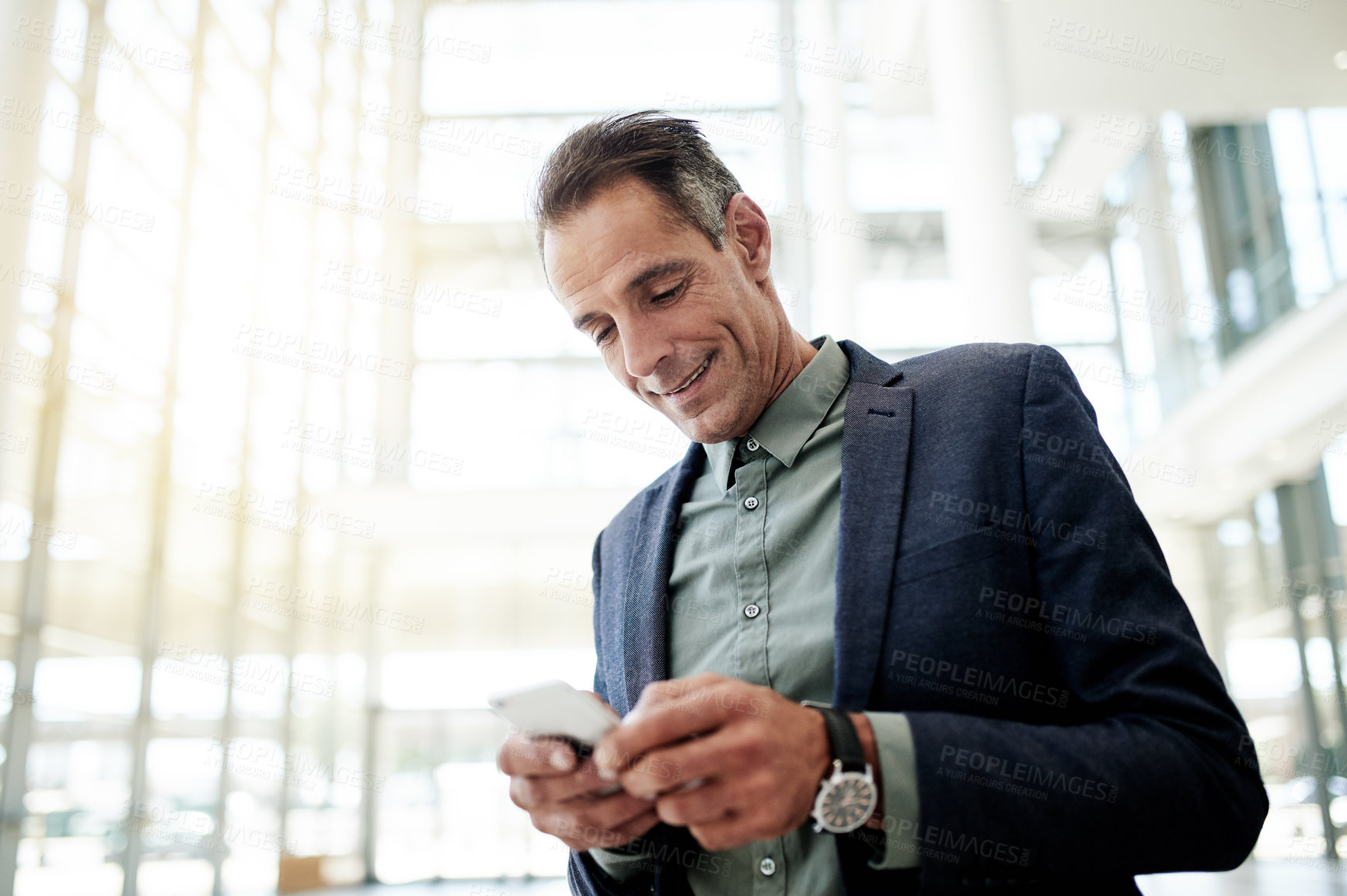 Buy stock photo Man, phone and scroll for real estate deal in lobby, low angle or contact for negotiation. Person, realtor and smartphone with app for property investing, smile and notification for building value