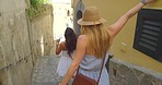 A happy woman holding her hat and making the peace sign while walking with her friend on holiday