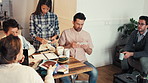 Diverse group of businesspeople looking at photos and drinking coffee during a meeting. A young businesswoman looking at fabric samples while her colleagues brainstorm and look at photos