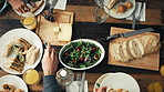 A group of friends having lunch together at a table from above. Friends at a party reaching for food on the table at brunch from above. A group of friends celebrating and eating a meal together