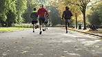 Slow motion of a diverse group of friends jogging through a park together. Back of a group of men and women running through a garden together. A group of friends exercising together in a park