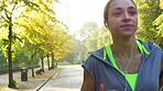 Content young woman listening to music through her earphones and jogging in the park. Young woman running through the park to workout in slow motion. Young woman running and listening to music