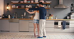 a young couple dancing in the kitchen together at home. Cheerful girlfriend and boyfriend playfully dancing in their kitchen in their pyjamas together. Couple having fun dancing in their apartment