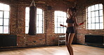 Fit young woman focused while jumping with a skipping rope. Active young hispanic woman at the gym skipping during her cardio routine using a rope. Sporty woman toning her body by jumping