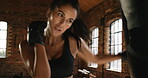 Powerful young hispanic athlete punching a bag in the gym during her cardio workout routine. Sporty fit woman focused on her boxing training routine in the gym.Strong athletic woman working out