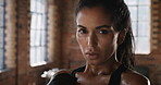 Serious athlete stretching her neck, wiping off sweat and taking a break from her cardio workout at the gym. Portrait of a strong fit woman ready for her boxing workout. A powerful woman in the gym