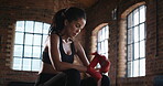 Hispanic athlete tired after her boxing exercise removing her support bandages. Sweaty athletic woman cooling down after her workout routine and removing protective bandages from her hands and wrists