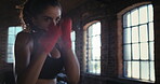 Focused athlete enjoying her cardio boxing workout at the gym. A strong Hispanic woman hitting a punching bag during her exercise routine. Powerful athlete using a punching bag for her training.