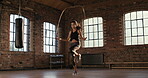 Serious young woman skipping at the gym. Young woman working on her fitness, skipping with a jump rope. Fit hispanic woman doing cardio and skipping at the gym. Woman jumping using a skipping rope