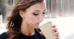 A young businesswoman drinking coffee while using her cellphone. Businesswoman in the city using her smartphone and drinking a cup of tea. Focused businesswoman drinking coffee