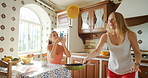A happy young woman using her cellphone to take a photo of her friend flipping a pancake