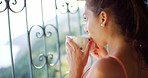 A young woman enjoying a cup of coffee while looking out of a window at the view