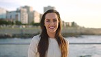 A smiling young woman on a seaside holiday relaxing on the promenade. A happy woman relaxing by the beach during her holiday at sunrise. A cheerful young woman enjoying the promenade at sunset