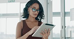 Beautiful mixed race businesswoman wearing spectacles using a digital tablet while walking in a office at work. Latin female employee walking and using a wireless device in a startup business