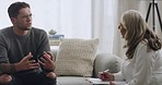 Young man on a couch in a session with a psychologist. Talking to his therapist about his problems and working through difficult emotions or memories while she makes notes