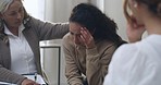 Latin woman having a breakdown during group therapy session about addiction. Friend giving support to depressed crying mixed race female at group psychological treatment