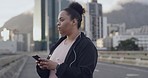 One young plus size woman using a cellphone and starting weight loss, focus on health, cardio, fitness and energy. Happy hispanic woman getting fit with a run and speed walking in the city