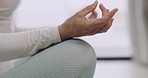 Closeup hand of a mature woman meditating at home. Senior adult practicing yoga in her house. One retired female in search of balance, inner peace and mindfulness. Meditate for a healthy body and mind