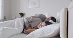 Young content mixed race couple taking a nap in a bed at home. Hispanic boyfriend and girlfriend sleeping together. Happy woman cuddling with her boyfriend. Husband and wife waking up in the morning