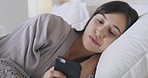 One beautiful mixed race woman looking annoyed while using her phone in bed. Young hispanic woman looking stressed and worrying before going to sleep. Feeling alone and anxious at home at night