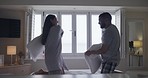 Young free mixed race couple having a playful pillow fight at home together. Hispanic husband and wife being affectionate and playing on a bed in a house. Boyfriend and girlfriend kissing and intimate