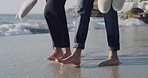 Closeup of a free young couple walking barefoot on a sandy beach and enjoying fresh air together on vacation. Mixed race lovers having a romantic sea holiday and enjoying quality time bonding outside 