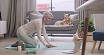 Woman meditating with a yoga tutorial online. Mature lady bending and stretching in balasana or extended childs pose while exercising with pet dog for tranquility, healthy lifestyle and inner peace