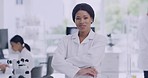 Portrait of a young scientist removing glasses on blur background in lab with coworkers. Confident African biologist standing with arms folded. Expert happy with medical findings at research facility