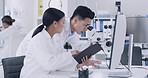 Young man and woman working at the lab. A man looking inside a microscope and a lady showing the results or reports. A focused team of researchers working in a laboratory. 