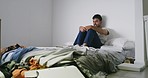 Mentally ill man with psychic disorder watching TV with different facial expressions. A mental person sitting on the bed has abnormal behavior while watching television and making unusual faces.  