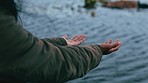 Unknown woman catching raindrops in her hands and standing alone outside. Playful woman playing in the rain and raising arms to catch water drops. Woman wearing a raincoat and enjoying the wet weather