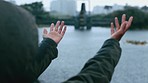 Woman catching raindrops in her hands and standing alone outside. Playful woman playing in the rain and raising arms to catch water drops. Woman wearing a raincoat and enjoying the wet weather