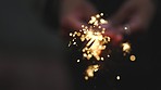 Closeup of a person holding and firing a sparkler in night celebration. Unrecognizable woman enjoying nightlife with a firecracker in evening. Festive person celebrating the holidays with fireworks