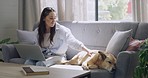 Freelance blogger typing on laptop after petting Africanis pet dog and domestic animal while working from a home living room in lockdown. Happy woman researching on technology and bonding with canine