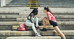 Two motivated female athletes stretching and talking before a workout in sports stadium. Fit, young man high fiving friends after training. Team of active and sporty athletes encouraging one another