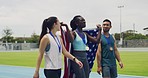 American female athlete gold medalist with a US flag celebrating. Happy African athletics winner walking with competitors on sports ground. Successful sports woman with her sports friends on a track
