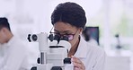 Female scientist using a microscope with glasses in a research lab. Young biologist or biotechnology researcher working and analyzing microscopic samples with the latest laboratory tech equipment