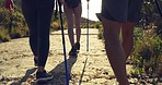 Group of three hiking friends with poles on a mountain trail outdoors. Young hikers walking in nature, seeing views and exercising while enjoying active and physical hobby. Staying fit and exploring