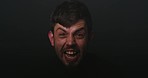 Face portrait of schizophrenic patient against flashing black background in studio with copy space. Insane, angry, crazy or mentally ill man screaming and shouting while suffering from schizophrenia