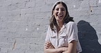 Portrait of a trendy young woman smiling and laughing with arms crossed against a wall on a sunny day. Happy, fashionable and cool hipster female with attitude feeling carefree, excited and confident